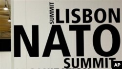 A man walks by a logo printed on a wall inside the NATO summit venue in Lisbon, Portugal on Thursday, Nov. 18, 2010. Heads of State of NATO member countries gather for a two day summit beginning on Friday, and will discuss such topics as Afghanistan and m