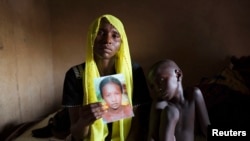 Rachel Daniel, 35, holds up a picture of her abducted daughter Rose Daniel, 17, at her home in Maiduguri, Nigeria, May 21, 2014.