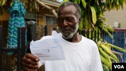 William Jones, upset with the unresponsiveness of his electric company, displays his monthly bill. “Answer the phone when you call them,” he complains. “Answer the phone.” (Photo: R. Taylor / VOA)