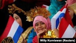  Seorang pelajar yang membawa bendera Indonesia dan belanda bereaksi di depan kamera saat bersiap menyambut Perdana Menteri Belanda Mark Rutte saat upacara penyambutan di Istana Presiden di Bogor, 7 Oktober 2019. (Foto: REUTERS/Willy Kurniawan)
