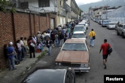 People line up outside a supermarket next to motorists queuing for gas near a gas station of the Venezuelan state-owned oil company PDVSA in San Cristobal, Venezuela, Nov. 10, 2018.