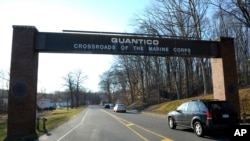 FILE - Cars pass under a sign at the entrance to the main gate at Quantico Marine Corps Base in Quantico, Va. The Marine Corps is considering offering perks to entice older, more experienced Marines to re-enlist as it builds up its cyber operations. 