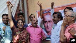 FILE - Friends of Indian naval officer Kulbhushan Jadhav celebrate the International Court of Justice order on Jadhav as they gather near a portrait of him in Mumbai, India, May 18, 2017. 