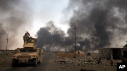 FILE - Iraqi security forces patrol as smoke rises from burning oil wells in Qayara, south of Mosul, Iraq, Aug. 31, 2016. As Iraqi and coalition forces prepare to move on Mosul, IS fighters reportedly are digging trenches around the city which they plan t