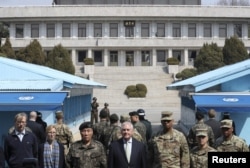 美国国务卿蒂勒森和美国上将、韩国上将在韩国和朝鲜之间的板门店停战村的南侧留影，北侧的朝鲜军人观看