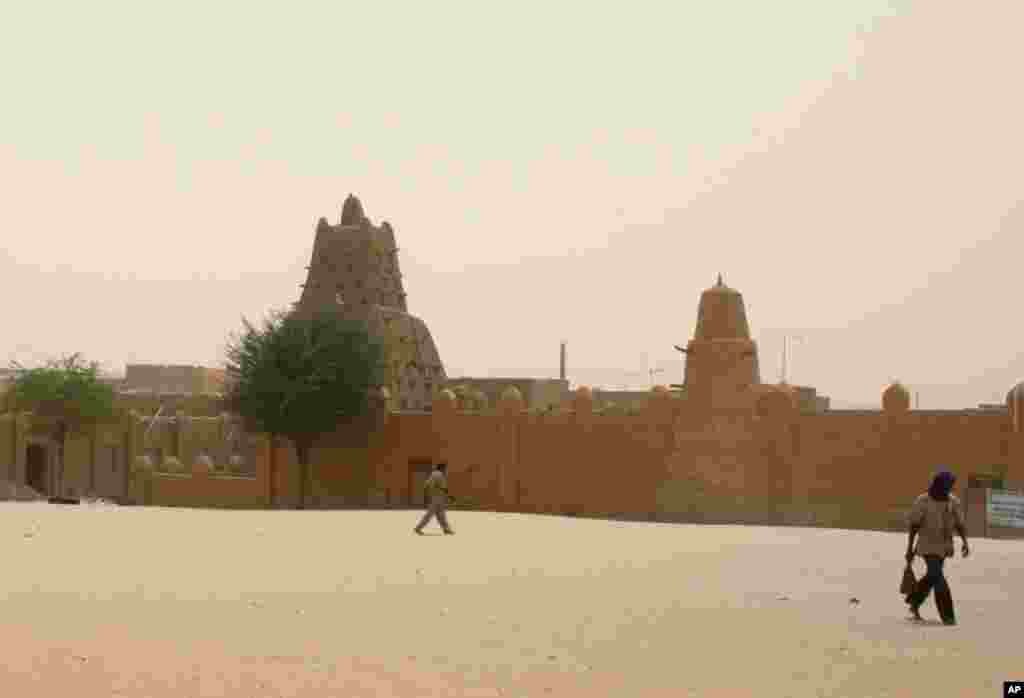 This April 11, 2012 photo shows people walking past the Sankore Mosque, a UNESCO World Heritage Site, in Timbuktu, Mali. 