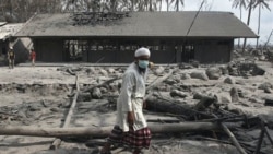 Seorang pria berjalan melewati bangunan sekolah di Cangkringan, Yogyakarta, yang terselimuti debu vulkanik dari letusan Gunung Merapi.