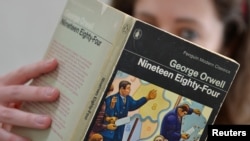 FILE - A reader poses for a photograph with a copy of George Orwell's "1984."