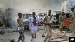 A Somali soldier helps a civilian who was wounded in a blast in the capital of Mogadishu, Somalia, Saturday, Oct. 14, 2017. 