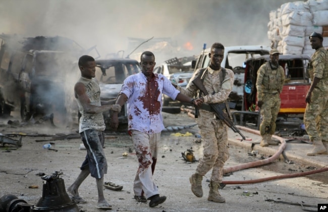 A Somali soldier helps a civilian who was wounded in a blast in the capital of Mogadishu, Somalia, Saturday, Oct. 14, 2017.