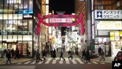 Warga berjalan-jalan di kawasan Shinjuku, Tokyo, Kamis, 7 Januari 2021, setelah PM Jepang Yoshihide Suga mengumumkan keadaan darurat mulai Jumat (8/1), seiring meningkatnya kasus positif Covid-19. (AP Photo/Hiro Komae)