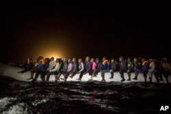 Pengungsi dan migran dari berbagai negara Afrika di atas perahu karet yang padat meninggalkan perairan Libya saat subuh, 5 Maret 2017.