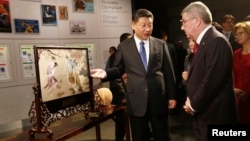 Chinese President Xi Jinping describes a gift showing a game of cuju to International Olympic Committee President Thomas Bach after a visit to the Olympic Museum in Lausanne, Switzerland, Jan. 18, 2017. 