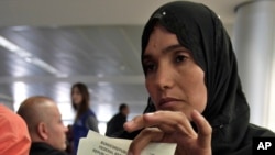 A Syrian refugee shows her immigration papers before boarding a flight to Germany for temporary relocation, at Rafik Hariri International Airport in Beirut, Lebanon, Sept. 11, 2013.