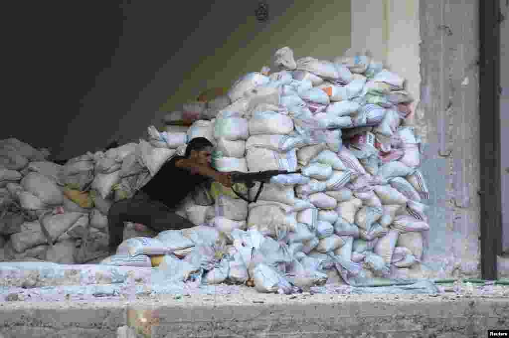 A Free Syrian Army fighter aims his weapon as he takes up a position behind sandbags in the al-Khalidiya neighborhood of Aleppo, August 4, 2013. 