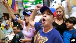 Arelys Lopez, foreground, leads a cheer as Venezuelans chant while watching televised news from their country at the El Arepazo Doral Venezuelan restaurant in Doral, Fla., April 30, 2019.