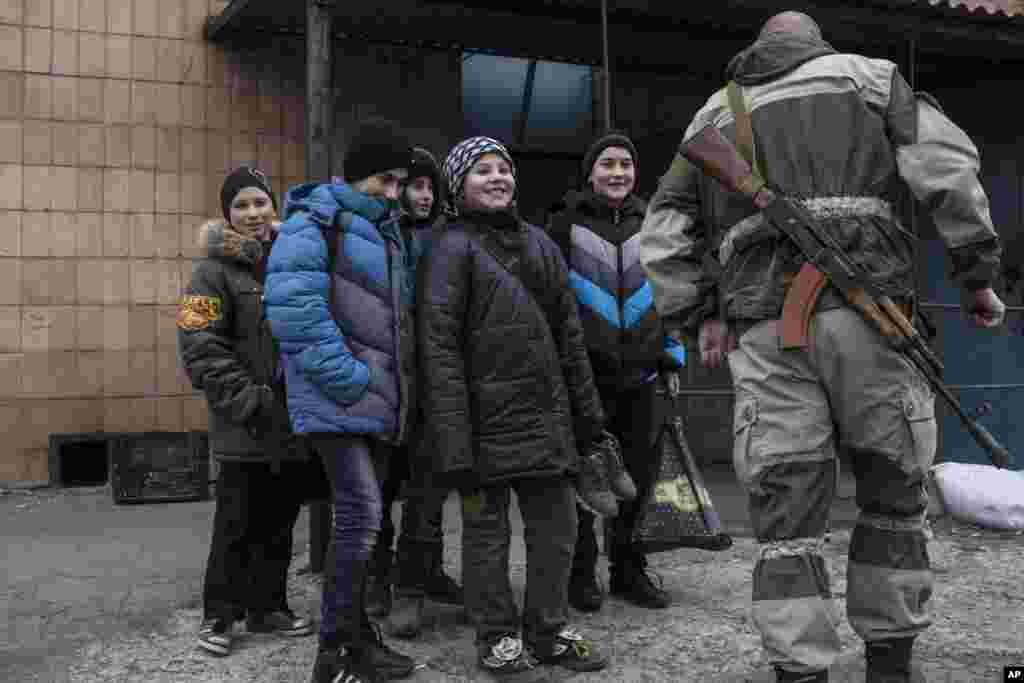 In a long-awaited development, Ukrainian forces and pro-Russian separatist fighters announced they are moving heavy weapons from the front line in eastern Ukraine. In this photo, a Ukrainian serviceman speaks with local schoolboys in the village of Chermalyk, eastern Ukraine,&nbsp; Feb. 26, 2015.