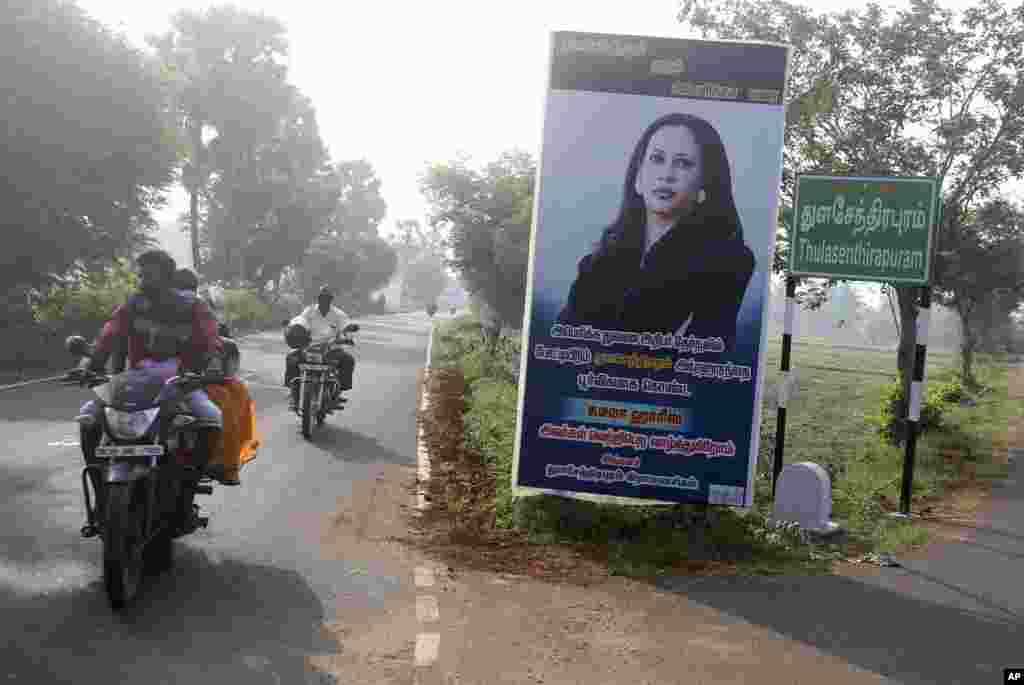 People ride past a billboard featuring U.S. democratic vice presidential candidate Sen. Kamala Harris at a crossing in Thulasendrapuram village, south of Chennai, Tamil Nadu state, India.