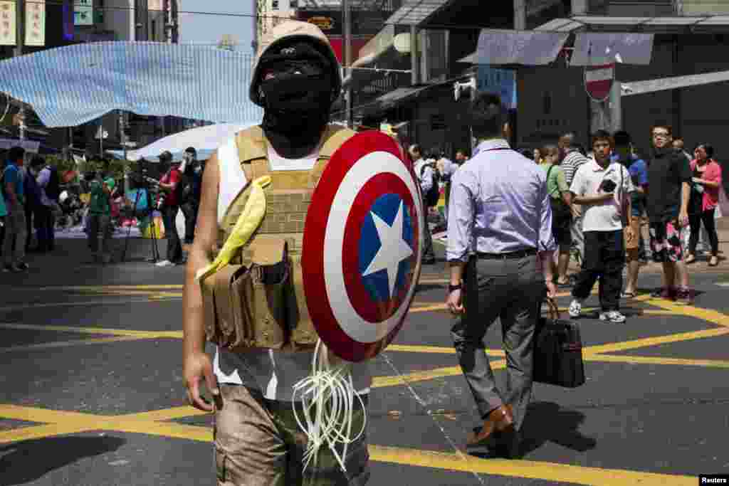 A protester of the Occupy Central movement carries a shield from the 'Captain America' comic book series as he stands on a main road at the Mong Kok shopping district in Hong Kong.