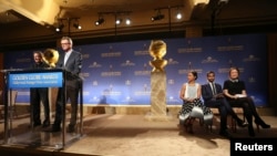 Hollywood Foreign Press Association President Theo Kingma speaks at the podium as (L-R) actors Zoe Saldana, Aziz Ansari and Olivia Wilde sit on stage at the announcement of nominations for the 71st annual Golden Globe Awards in Beverly Hills, California, 