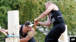 Competitors cut a tree trunk with axes in Munich, Germany.