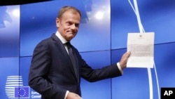 FILE - EU Council President Donald Tusk grimaces at a press conference in Brussels March 29, 2017, showing the letter he received signed by Britain's Prime Minister Theresa May formally triggered the beginning of Britain's exit from the EU.