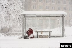 Seorang tunawisma duduk di halte bus saat terjadi badai salju di Washington, AS, 3 Januari 2022. (Foto: REUTERS/Kevin Lamarque)
