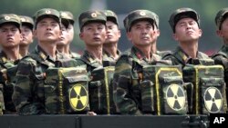 FILE- North Korean soldiers turn and look towards their leader Kim Jong Un from a military parade vehicle as they carry packs marked with the nuclear symbol during a ceremony in Pyongyang, North Korea, July 27, 2013.