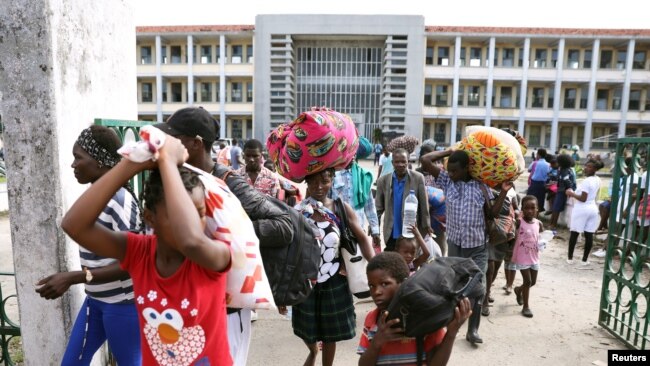 Evacuees from Buzi village carry their belongings as they leave a school that was used as a displacement center, after Cyclone Idai, in Beira, Mozambique, March 25, 2019.