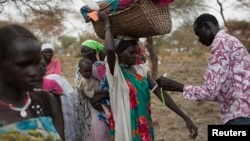 A mother carrying her baby in a basket is screened for malnutrition at a joint UNICEF-World Food Program Rapid Response Mission, which delivers critical supplies and services to those displaced by conflict, in Nyanapol, South Sudan, March 3, 2015.