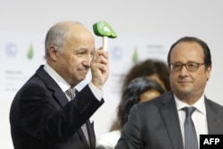 Foreign Affairs Minister and President-designate of COP21 Laurent Fabius, left, waves the official gavel of the conference, as France's President Francois Hollande looks on, after adoption of a historic global warming pact, Dec. 12, 2015.