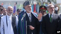 Afghan President Hamid Karzai, center, speaks in front of local and international media representatives as presidential candidates Abdullah Abdullah, right, and Ashraf Ghani Ahmadzai, left, listen during the Independence Day ceremony in Kabul, Afghanistan