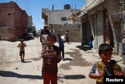 FILE - Syrian children and a man are seen carrying food aid in Douma, near Damascus, Syria, Aug. 6, 2017.