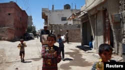 FILE - Syrian children and a man are seen carrying food aid in Douma, near Damascus, Syria, Aug. 6, 2017.