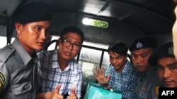 FILE - Detained Myanmar journalists Wa Lone, left, and Kyaw Soe Oo, third from right, are escorted by police from the courthouse as they are taken to prison after the first day of trial in Yangon, July 16, 2018.