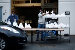 Hazim Macky (kiri) dan Shaharyar Aarbi membagikan makanan berbuka puasa gratis ke para anggota di luar gedung Asosiasi Muslim Puget Sound pada hari pertama Ramadan saat wabah virus corona, di Redmond, Washington, 24 April 2020. (Foto: Reuters)