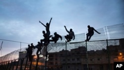 Des migrants africains grimpent une barrière entre le Maroc et l’enclave de Melilla, le 28 mars 2014. 