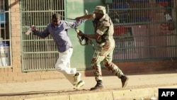 A Zimbabwean soldier beats a man in a street of Harare on August 1, 2018 as protests erupted over alleged fraud in the country's election. 