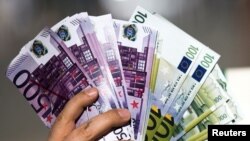 An activist shows fake banknotes during a demonstration outside the European Commission (EC) headquarters ahead of statements by the EC on the effectiveness of existing measures against tax evasion and money-laundering.