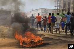 Protesters walk past a burning tire in the eastern Congolese town of Beni, Dec. 28, 2018.