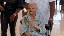Viola Fletcher, center, the oldest living survivor of the Tulsa race massacre, holds a rose she received as she arrives for a luncheon honoring survivors Saturday, May 29, 2021, in Tulsa, Okla. (AP Photo/Sue Ogrocki)