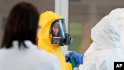 Russian President Vladimir Putin, center, wearing a protective suit visits the hospital for coronavirus patients in Kommunarka settlement, outside Moscow, Russia, Tuesday, March 24, 2020.