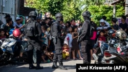 Anggota polisi anti-terorisme Densus 88 menutup jalan saat menggeledah sebuah rumah di Surabaya, Jawa Timur, 19 Juni 2017. (Foto: AFP/Juni Kriswanto).