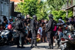 Anggota polisi anti-terorisme Densus 88 mengepung sebuah jalan ketika mereka menggeledah sebuah rumah di Surabaya, Jawa Timur, pada 19 Juni 2017, menyusul penangkapan seorang pria yang diduga terkait dengan kelompok Negara Islam (ISIS). (Foto: AFP/Juni Kr.)