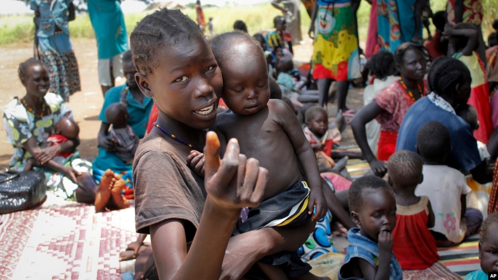 In this photo taken Sept. 16, 2016, a young girl holds a child at a UNICEF clinic for severely malnourished children in Aweil, South Sudan.