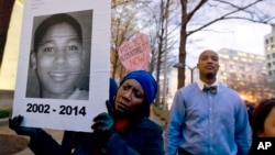 FILE - Tomiko Shine holds up a picture of Tamir Rice, the 12 year old boy fatally shot on Nov. 22 by a rookie police officer, in Cleveland, Ohio, Dec. 1, 2014.