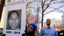 FILE - Tomiko Shine holds up a picture of Tamir Rice, the 12 year old boy fatally shot on Nov. 22 by a rookie police officer, in Cleveland, Ohio, Dec. 1, 2014.