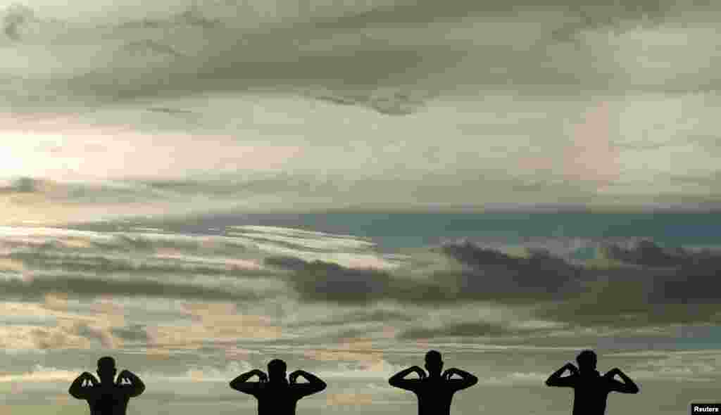 A group of men perform physical exercise training as the sun sets at Galle Face green in Colombo, Sri Lanka, January 9, 2013. 