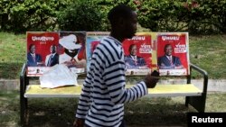 A man passes by posters of presidential candidates Uhuru Kenyatta and Prime Minister Raila Odinga in Nairobi, March 8, 2013. 