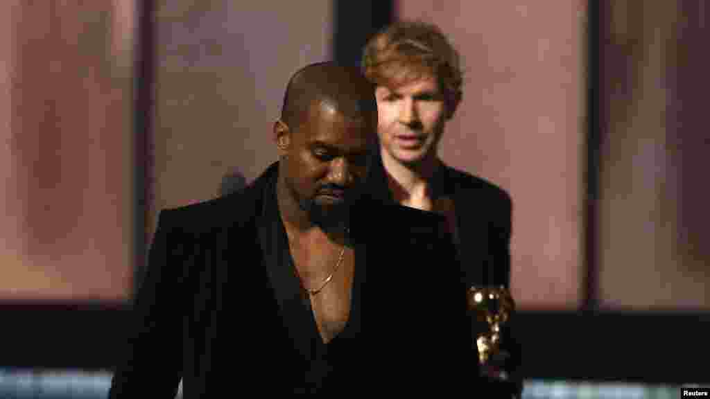 Beck, atrás, observa Kanye West, que subiu ao palco depois de Beck ter recebido o Grammy para Melhor Album do Ano com&nbsp; &quot;Morning Phase&quot;. West já o tinha feito na gala do ano anterior, quando tirou o galardão a Taylor Swift na 57&ordf; gala anual dos Prémios Grammy, Los Angeles, Califórnia, Fev. 8, 2015.